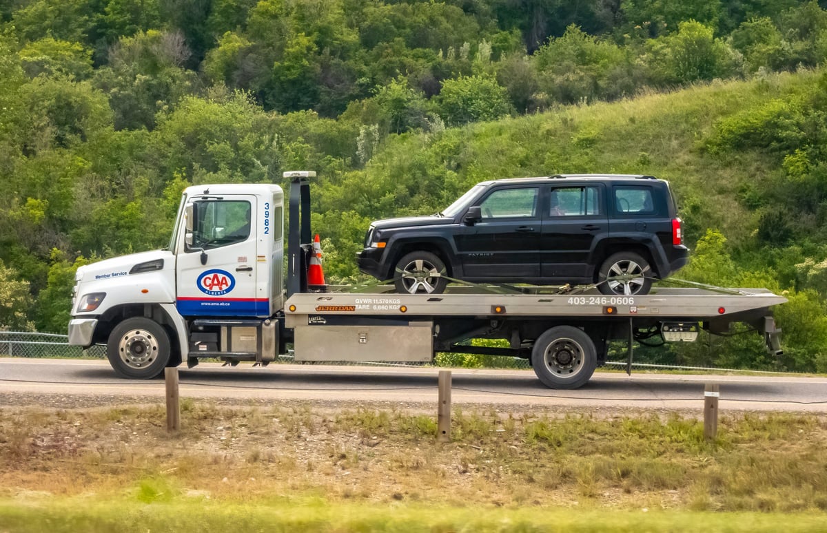 Flatbed tow truck carrying a vehicle, symbolizing reliable junk car removal