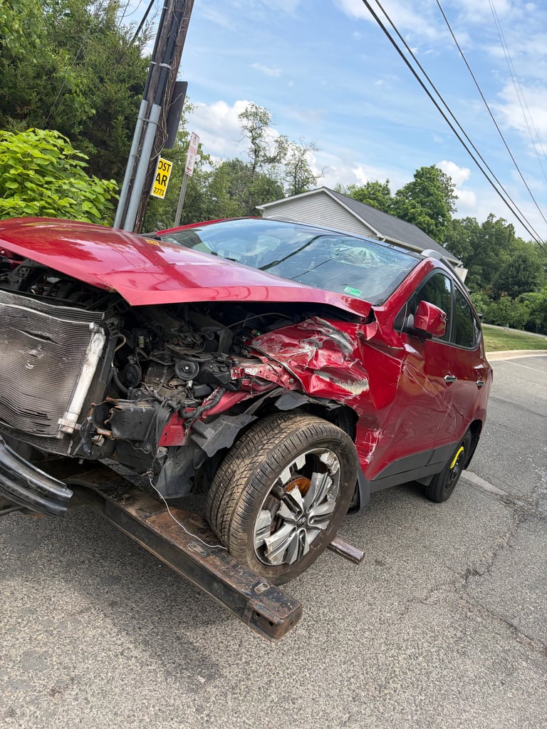 Red car severely damaged in front-end collision against wooden utility pole on residential road