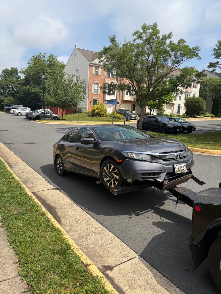 Gray Honda Civic sedan parked on residential street with apartment buildings and trees in background