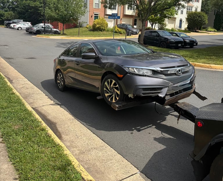 Gray Honda Civic sedan parked on a residential street next to a sidewalk with green grass and trees